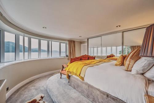 a bedroom with a large bed and windows at Loch Ness Mansion in Invermoriston