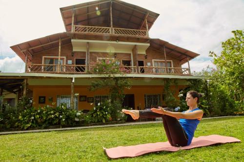 une femme faisant du yoga devant une maison dans l'établissement Finca Hotel Betel, à San Carlos