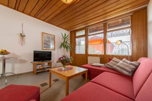 a living room with a red couch and a table at Ferienwohnung Haus Inge in Moosbach