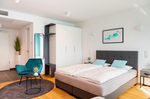 a bedroom with a large bed and a green chair at SERVENTO Boardinghouse in Erlangen