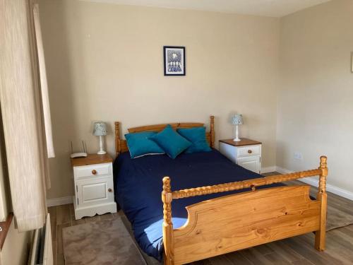 a bedroom with a wooden bed with blue pillows at Milo's Cosy Cottage Giant's Causeway in Bushmills