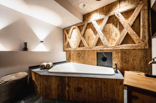 a bath tub in a room with a wooden wall at Wellness Hotel Alpenhof in Zermatt