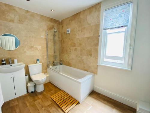 y baño con bañera, aseo y lavamanos. en Chiswell Cottage a large family nr WPNSA & Beach, en Castletown