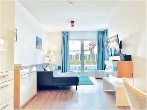 een woonkamer met een blauwe bank en een raam bij Apartments Boardinghaus Norderney in Norderney