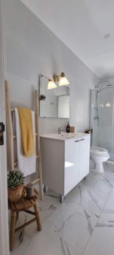 a white bathroom with a sink and a toilet at Canto da Rocha Guesthouse in Almada