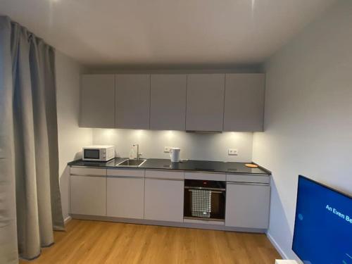 eine Küche mit weißen Schränken und einer Mikrowelle in der Unterkunft New Luxury Studio in the Heart of Kirchberg -D in Luxemburg (Stadt)