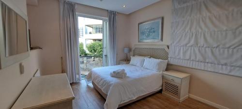1 dormitorio con cama blanca y ventana en V&A Waterfront Marina Family Apartment 101 Altmore, en Ciudad del Cabo