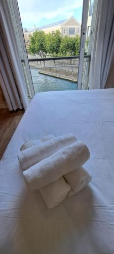 duas toalhas sentadas em cima de uma cama com uma janela em V&A Waterfront Marina Family Apartment 101 Altmore em Cidade do Cabo