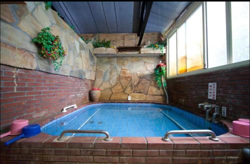 a swimming pool in a building with a brick wall at Ming Ren Hotspring Hotel in Jiaoxi