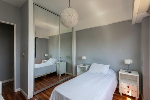 Schlafzimmer mit einem Spiegel und einem weißen Bett in der Unterkunft HOUSE LORCA in Buenos Aires