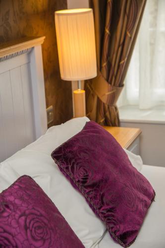 two purple pillows on a bed with a lamp at The Grove in St. Davids