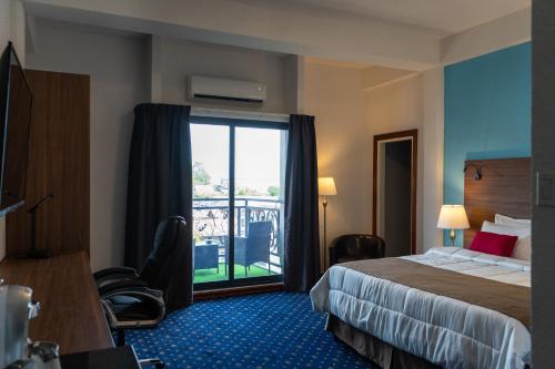 a hotel room with a bed and a balcony at Royal Breeze Paramaribo in Paramaribo