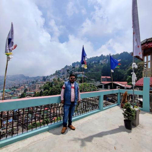 a man standing on a balcony with a view of a city at The Silver Spring Homestay in Darjeeling