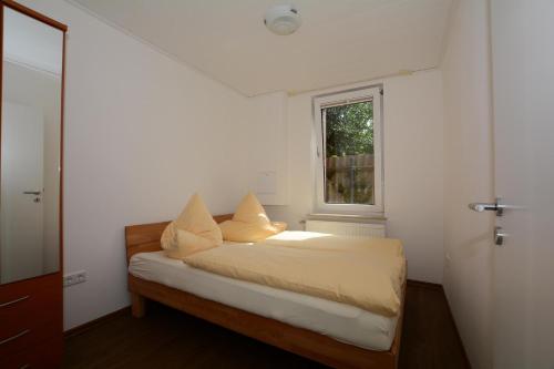 Schlafzimmer mit einem Bett mit weißer Bettwäsche und einem Fenster in der Unterkunft "Gästehaus Flandern" 5 in Borkum
