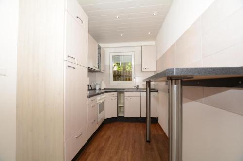 a kitchen with white cabinets and a wooden floor at Gaestehaus-Flandern-5 in Borkum
