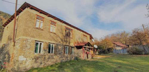 an old brick house with a grass yard next to it at Tsknari Oda in Oni