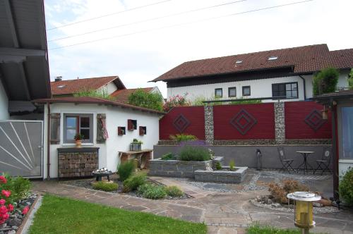 a backyard with a white house and a red fence at Ferienwohnung & App. Rosemarie in Bad Birnbach