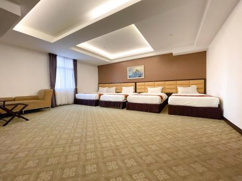 a hotel room with four beds and a couch at Hallmark Crown Hotel in Melaka