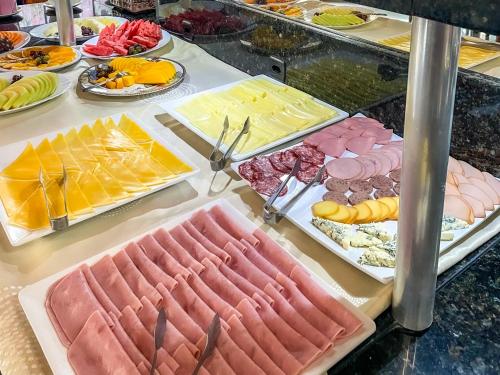 a buffet filled with different types of meats and cheese at Hotel & Pousada Sonho Meu in Florianópolis