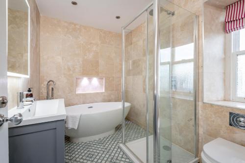a bathroom with a tub and a sink and a shower at East Cottage * Wood Burning Hot Tub * Garden in St. Andrews