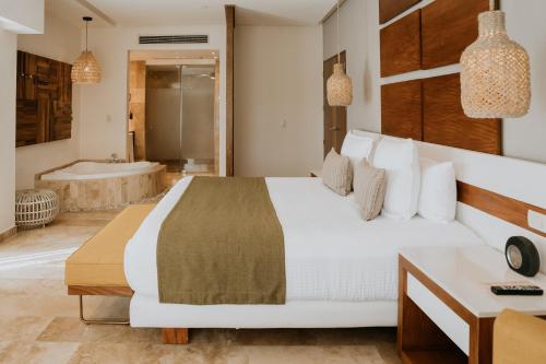 a bedroom with a large bed and a bath tub at The Reef 28 Hotel & Spa - Luxury Adults Only - All Suites - With Optional All Inclusive in Playa del Carmen