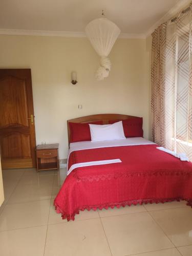 a bedroom with a red bed with a red blanket at SERENITAS ApartHotel in Kigali