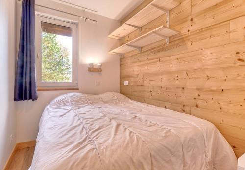 łóżko w pokoju z drewnianą ścianą w obiekcie Vacances face a la montagne w mieście Génos