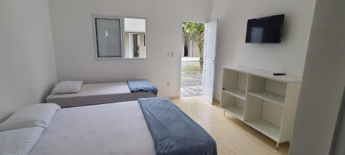 1 dormitorio con 1 cama, TV y puerta en Pousada Village Maitinga - suítes en Bertioga