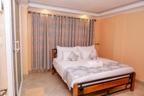 a bedroom with a large bed with a window at TRIPLINQ HOTEL & RESORT Meru in Nkubu