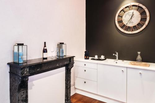 uma casa de banho com um lavatório e um relógio na parede em La Maison des Courtines em Beaune