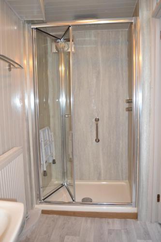 a shower with a glass door in a bathroom at Spacious ground floor apartment. No 1A The Stables in Llanfyllin