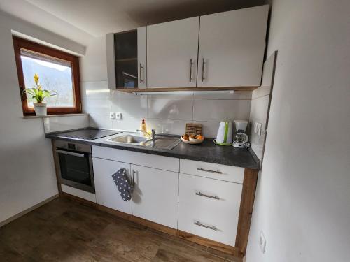 a kitchen with white cabinets and a sink and a window at Apartments Irena in Bohinj