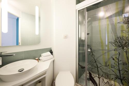 une salle de bain avec un lavabo et une douche dans l'établissement ibis Styles Bordeaux Begles Arena, à Bègles