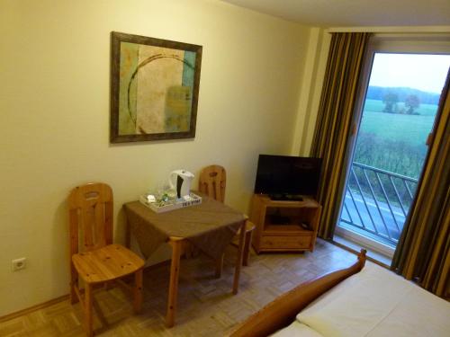 a room with a table and chairs and a television at Gästehaus Grunewald Bed & Breakfast in Heiden