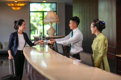 een man en twee vrouwen die handen schudden aan een bar bij Nam Cuong Hai Duong Hotel in Hải Dương