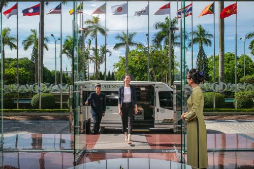 un hombre y una mujer parados frente a una furgoneta en Nam Cuong Hai Duong Hotel en Hải Dương