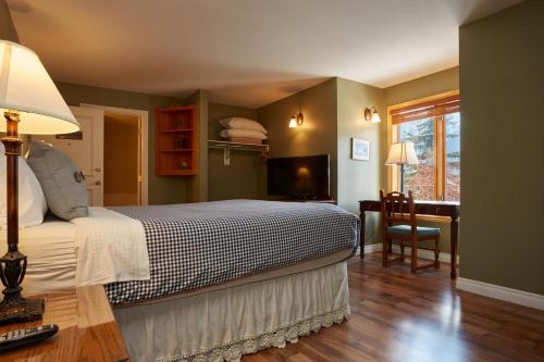 a bedroom with a bed and a desk and a window at Lady MacDonald Country Inn in Canmore