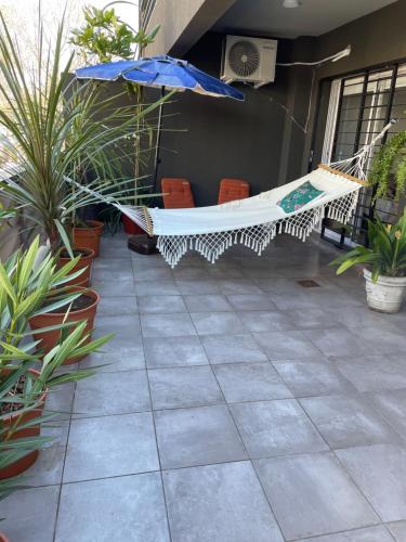 eine Hängematte auf einer Terrasse mit Stühlen und einem Sonnenschirm in der Unterkunft Ampio Balcone in Buenos Aires