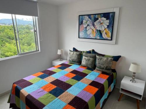 Un dormitorio con una cama colorida y una ventana en HERMOSO APTO CON VISTA a LAS MONTAÑAS DEL QUINDÍO CERCA de TODO, en Armenia