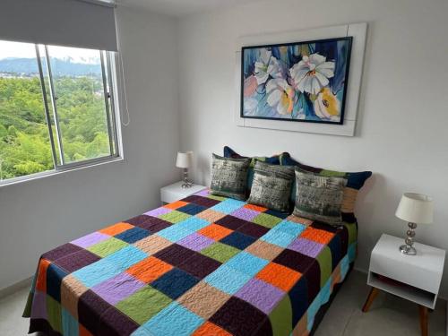a bedroom with a colorful bed and a window at HERMOSO APTO CON VISTA a LAS MONTAÑAS DEL QUINDÍO CERCA de TODO in Armenia