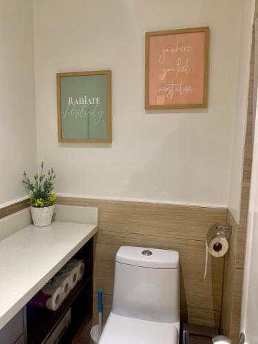 a bathroom with a toilet and two pictures on the wall at Elaiza's Cozy Home - Matina Enclaves Building C Unit 815 in Davao City