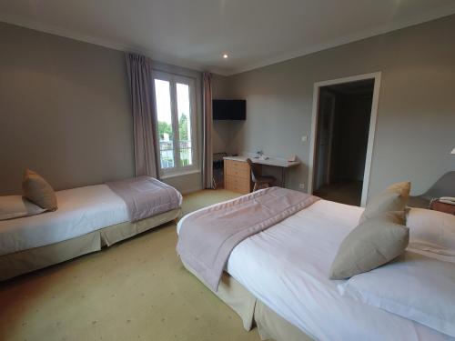 a hotel room with two beds and a window at Hotel Le Continental in Forges-les-Eaux