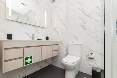 a white bathroom with a toilet and a mirror at Casa do Nilo in Sesimbra