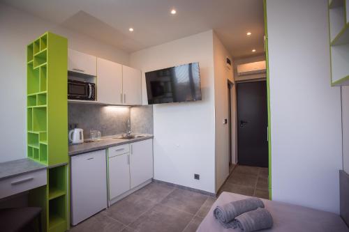 a kitchen with white cabinets and green accents at DORM BG pet-friendly Aparthotel in Stara Zagora