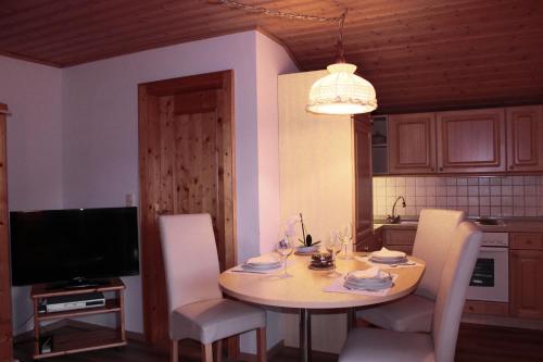 eine Küche mit einem Tisch mit Stühlen und einem TV in der Unterkunft Landhaus Johanna in Dorfgastein