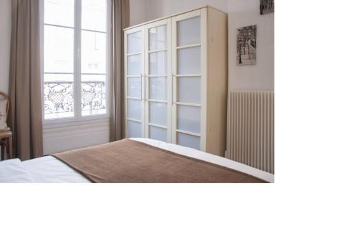 1 dormitorio con cama y ventana grande en La petite maison parisienne, en Levallois-Perret