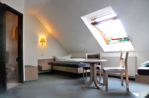 Habitación con cama, mesa y sillas. en Hotel Garni Haus Dornheim, en Obertshausen