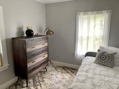 a bedroom with a dresser and a bed and a window at Spanish Town / Downtown Apartment in Baton Rouge