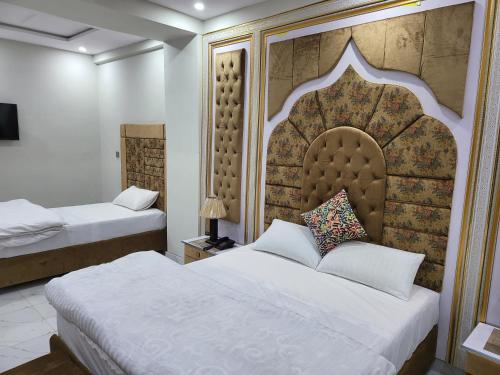 a bedroom with two beds and a large headboard at Relax Inn in Lahore