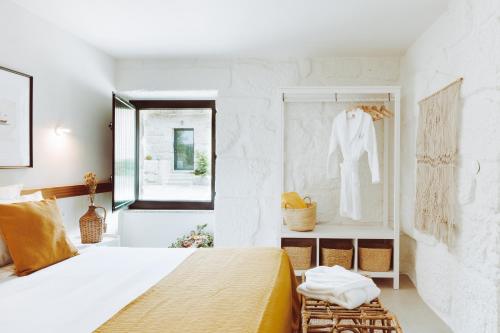 a white bedroom with a bed and a window at Oliveiras Village — Agroturismo in Amarante